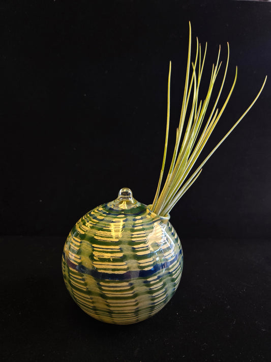 Decorative glass ornament with straw-like extensions on a black background